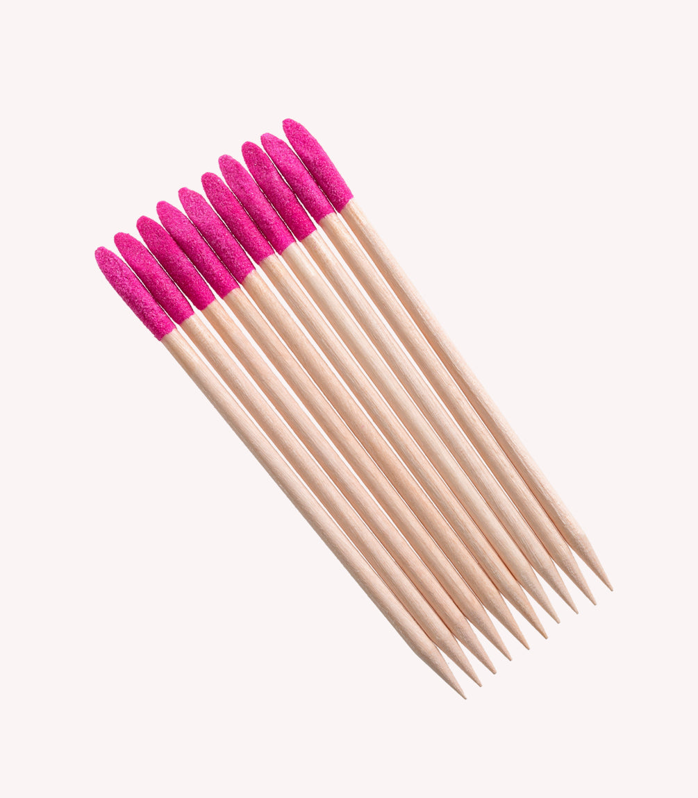Ten wooden toothpicks with pink tips on a white background.