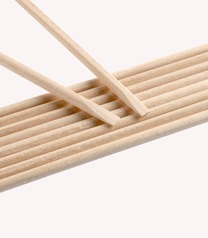 Two wooden sticks resting on a row of ten parallel wooden sticks on a white background.