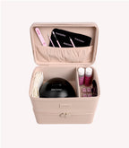 An open pink makeup case with a black LED nail lamp, nail files, brushes, nail polish bottles and other manicure accessories.