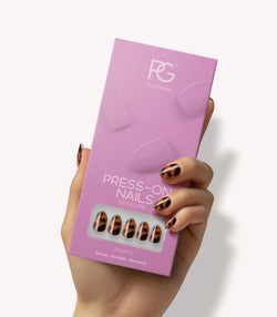 Hand holding Pink Gellac 2007 Tortoise Touch press-on nails in their packaging.