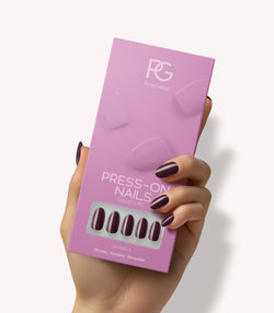 Hand holding Pink Gellac 332 Sangria Red press-on nails in their packaging.