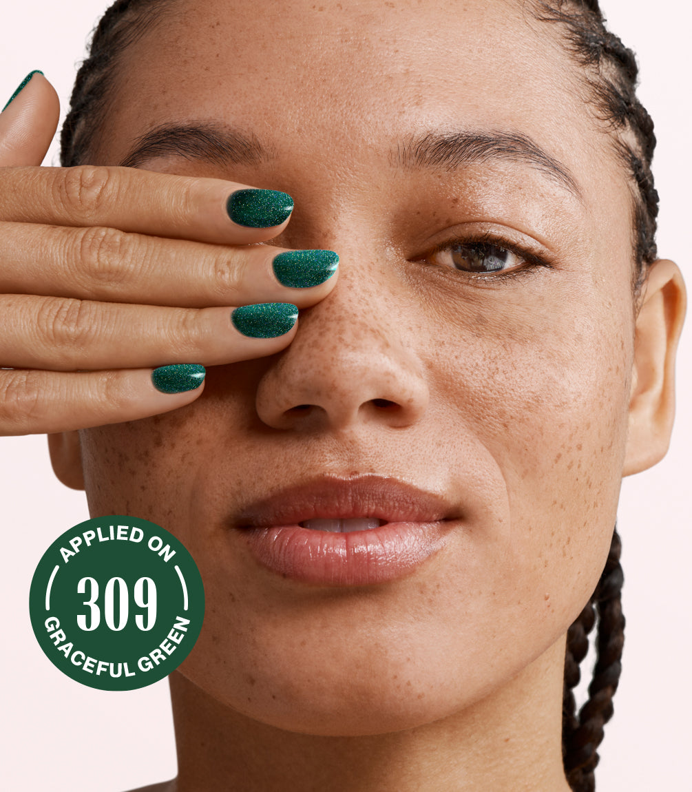 Woman with braided hair covers one©©eye with her hand and shows green nail polish, with a circular text "309 Applied on Graceful Green".