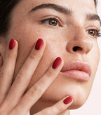 Close-up of a woman with Pink Gellac 109 Lipstick Red manicured nails near her face.
