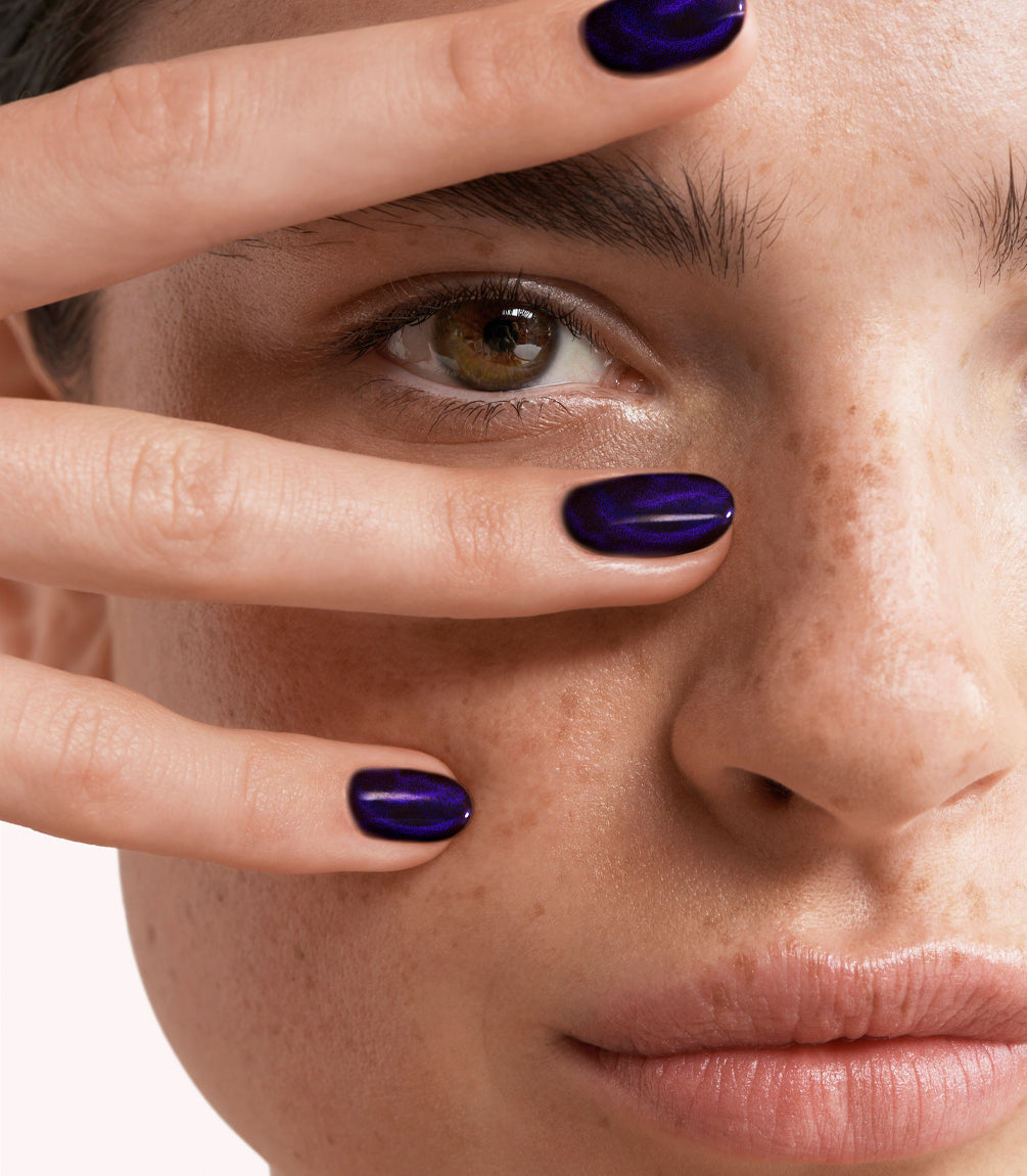 Close-up of a woman with Pink Gellac Cat Eye Majestic Amethyst manicured nails near her face.