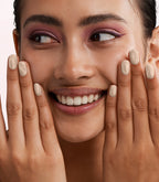Close-up of a woman with Pink Gellac Cat Eye Sandy Citrine manicured nails near her face.