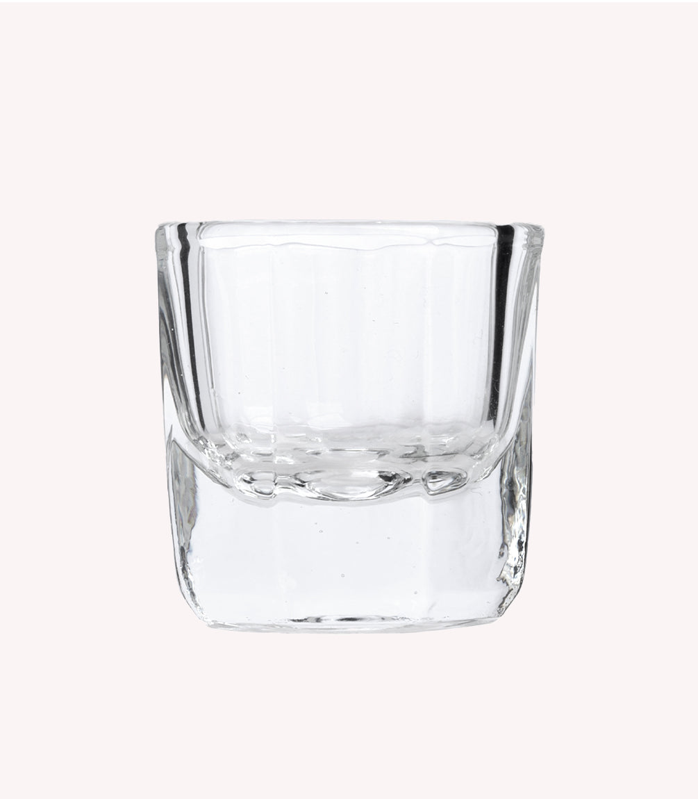 Transparent, thick-walled glass with a square shape on a light background.