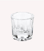 An empty, transparent shot glass against a neutral, light background.