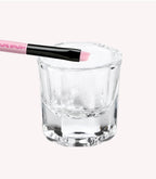 Glass cup with a pink brush on top.