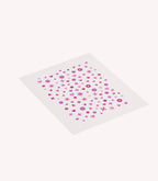 A sheet of pink and purple nail stickers in various shapes such as flowers, hearts and dots.