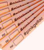 Close-up of several pink markers with the inscription "#pinkgellac" and an empty space for a number.