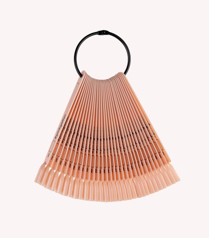A fan of nail tips in different nude shades, attached to a black ring.