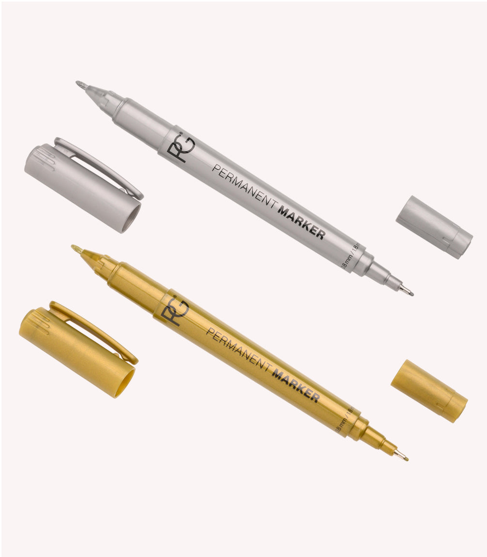 Two permanent markers, one silver and one gold, with their caps loose next to them.