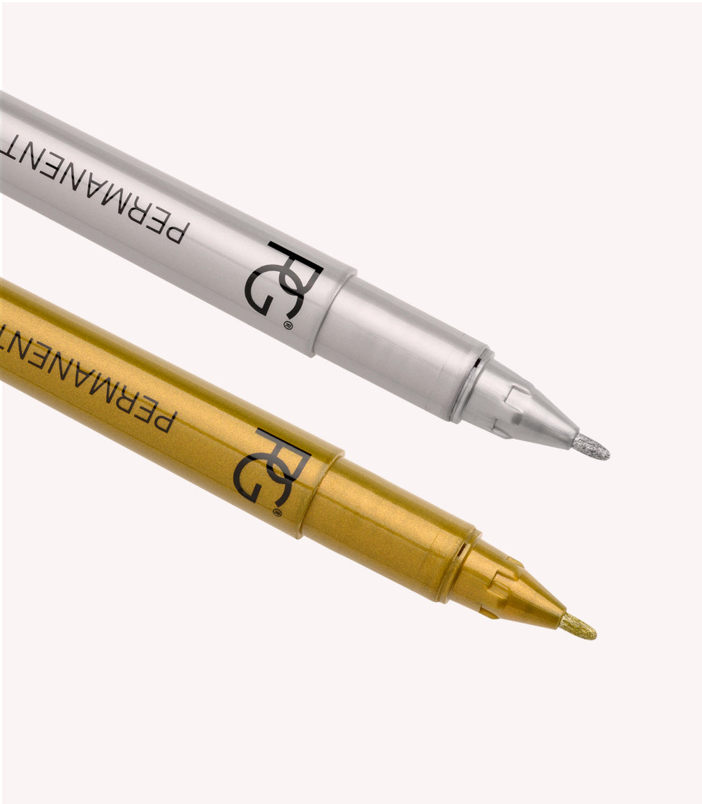 Two permanent markers, one©©silver and one©©gold, lying on a light background.