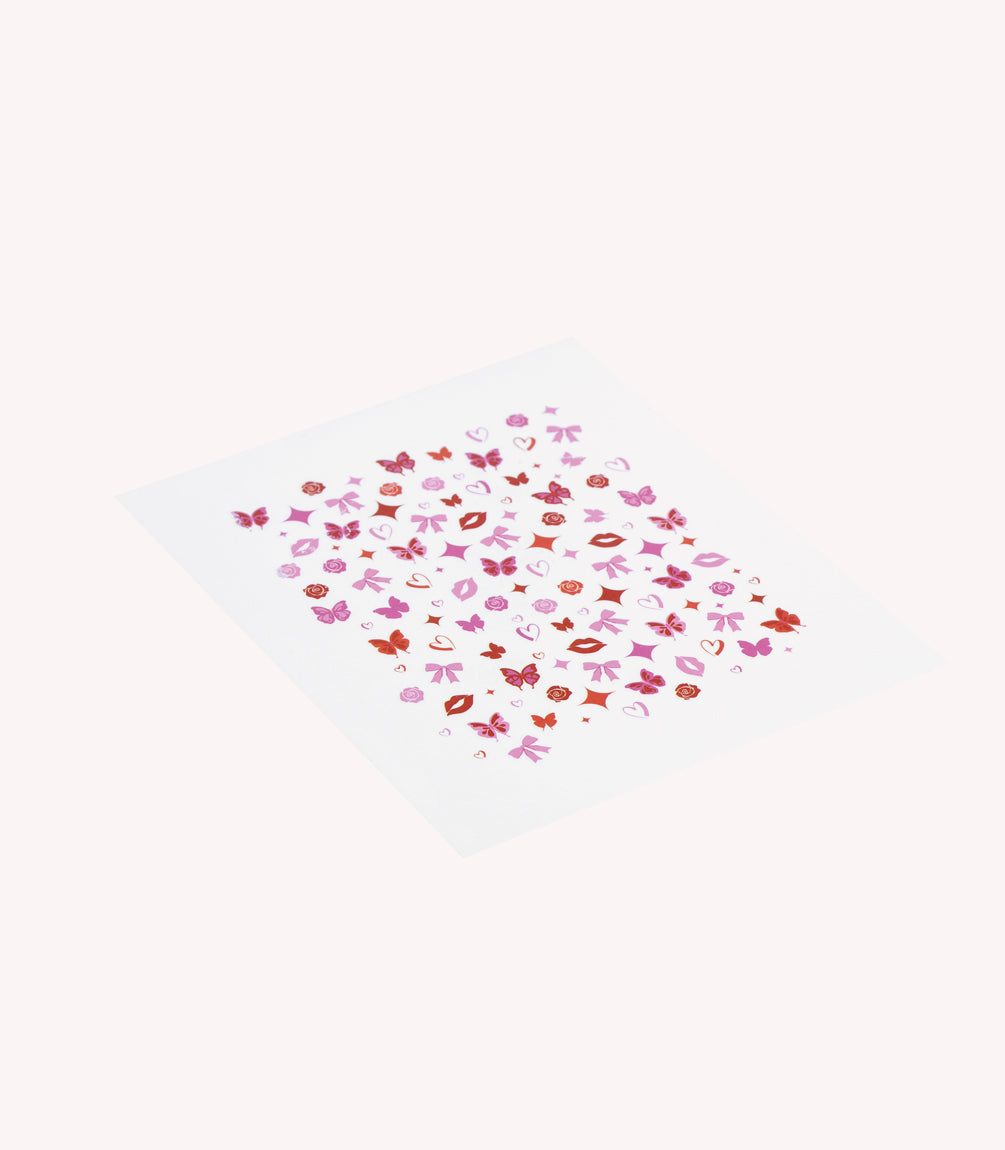 A sheet with colorful nail stickers including butterflies, flowers, lips and hearts in red and pink tones.