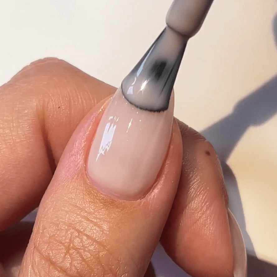 Close-up of a hand applying nail polish to a nail with a brush.
