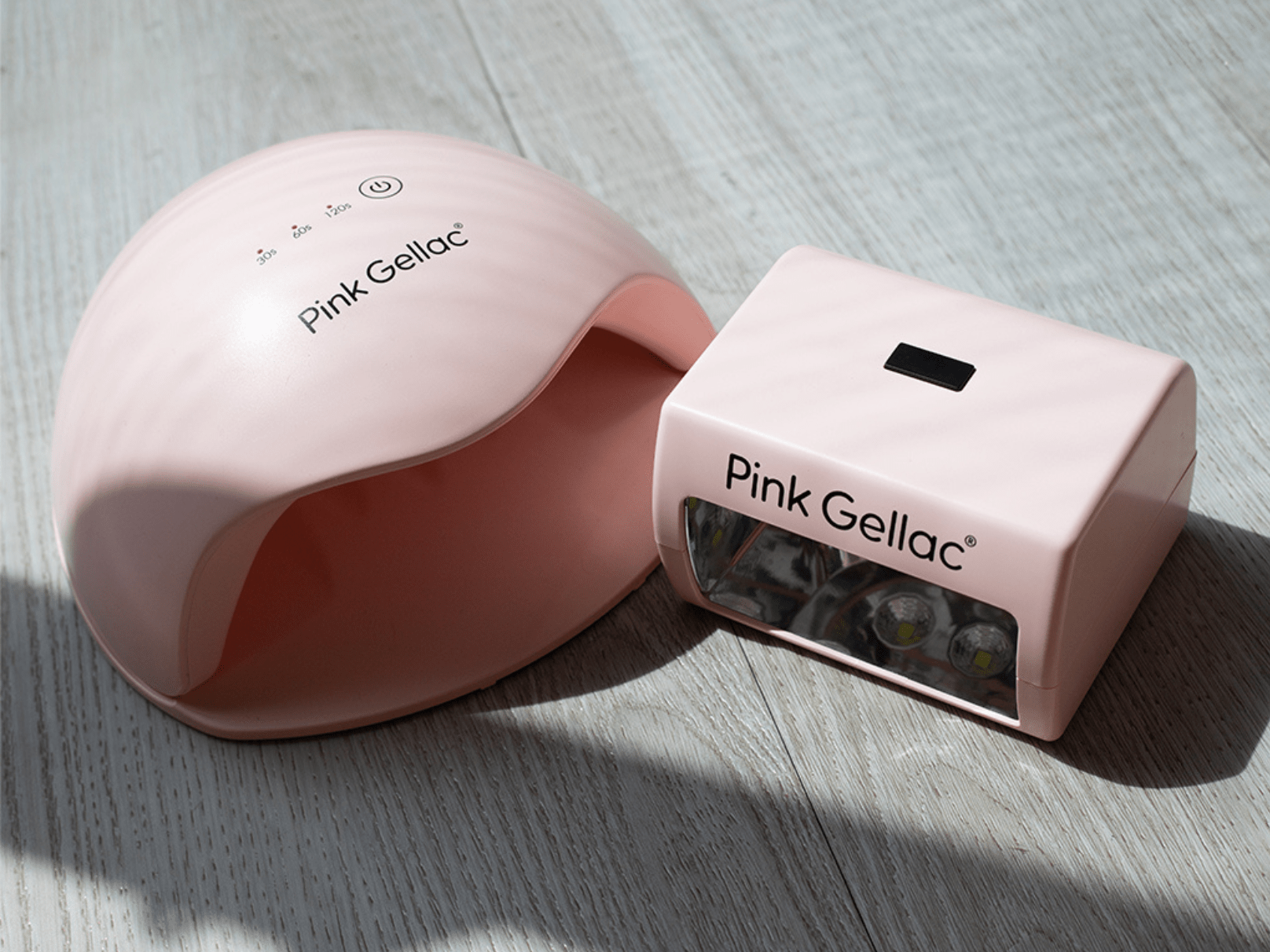 Pink nail dryers from the brand Pink Gellac on a light wooden surface.