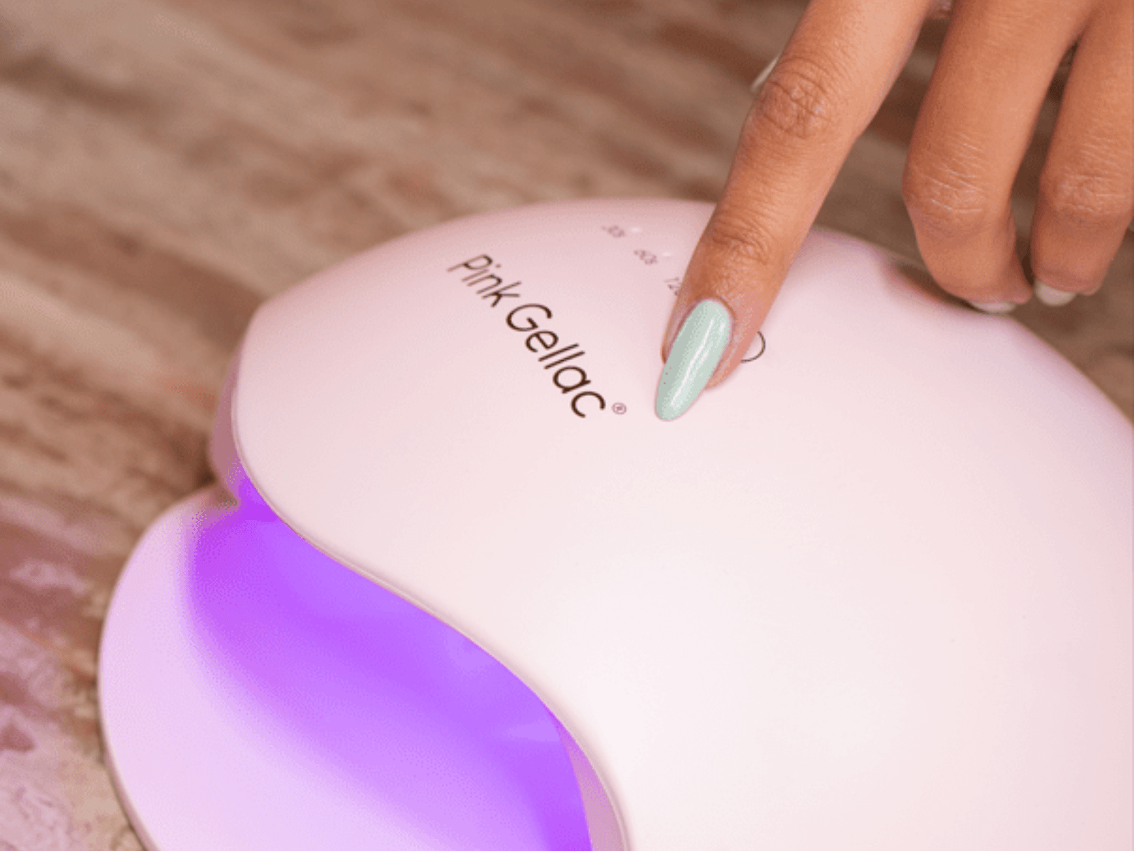 Woman with blue-painted nails operates a UV lamp for nails of the Pink Gellac brand.