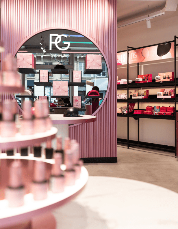 A stylish store interior with pink tones, round mirrors and shelves full of cosmetics and skincare products.